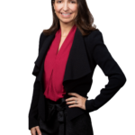 Eva, a professional woman with shoulder-length dark brown hair and a warm smile, is wearing a black blazer over a vibrant red blouse, paired with black trousers. She stands confidently with one hand on her hip, exuding poise and professionalism against a transparent background.