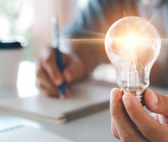 Innovation through ideas and inspiration ideas. Human hand holding light bulb to illuminate, idea of creativity and inspiration concept of sustainable business development.